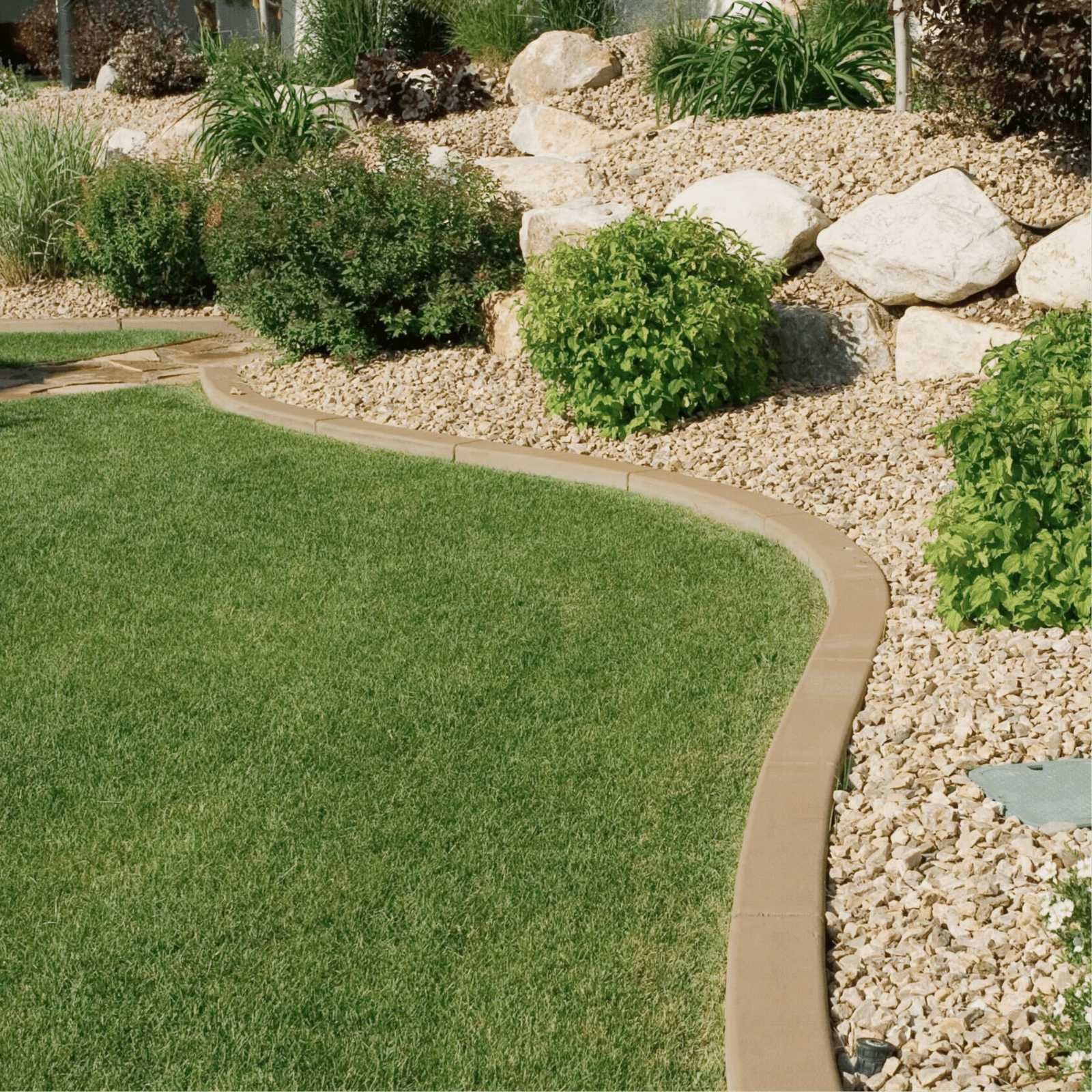 Professional landscape edging with lush green lawn bordered by decorative stone and shrubs, designed by Georgia Roots Landscaping in Warner Robins. Clean lines and durable hardscaping create a polished, low-maintenance yard that boosts curb appeal and enhances outdoor living spaces.