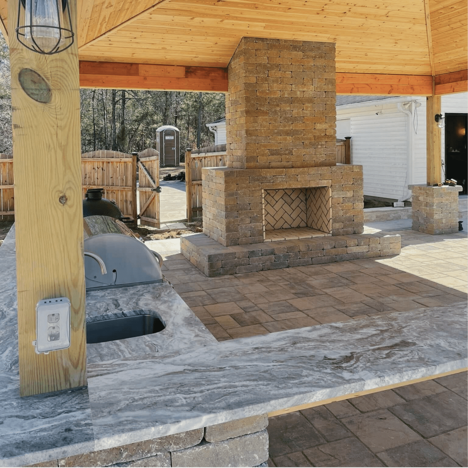 Custom outdoor kitchen and covered pavilion with stone fireplace, built-in grill, and spacious countertop designed by Georgia Roots Landscaping. Perfect for year-round entertaining, this backyard design blends functionality, style, and durable materials for the ultimate outdoor living experience.